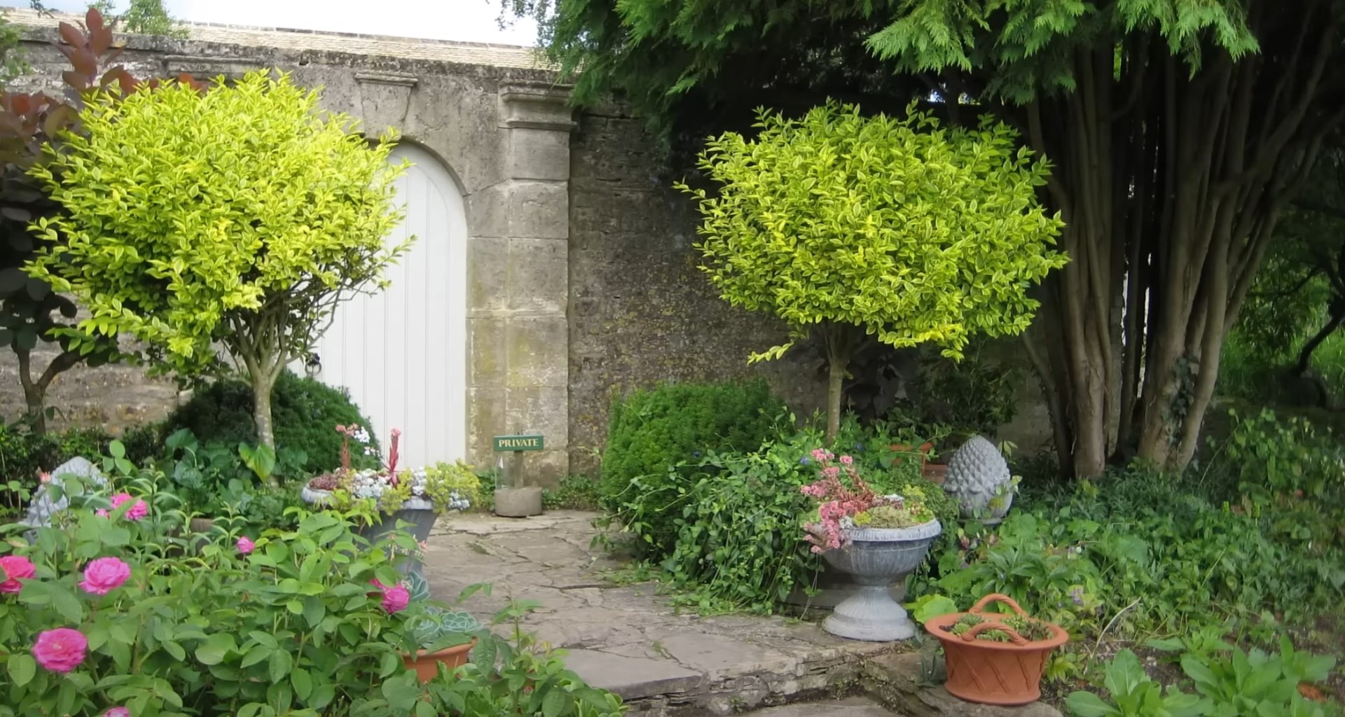Classic garden design with natural stone pathways and established plant collections Traditional garden landscape with stone pathways, mature plantings, and decorative features
